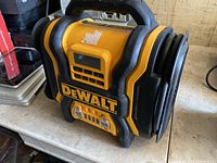 DeWalt DXAEPS14 jump starter and portable power station in yellow and black with digital display, buttons, and attached air compressor hose.