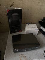Photo showing three items: Rogers Ignite Internet router in box, Bell DVR black box, Bell wifi extender in white box on a table with worn surface.