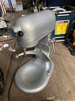 Silver KitchenAid Professional 600 Series bowl-lift stand mixer shown on workshop floor with signs of wear.