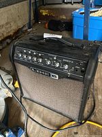 Line 6 Spider IV 15 guitar amplifier angled view showing control panel, handle, and speaker grille in industrial setting.