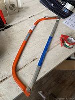 Orange and silver Mastercraft bow saw on a white workbench showing the saw blade and frame.