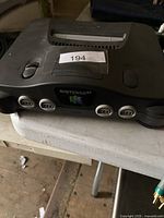 Front angled photo of the grey Nintendo 64 console showing power switch, reset button, four controller ports, cartridge slot and Nintendo 64 emblem.