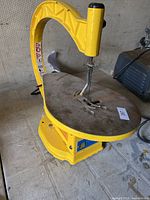 Full side view of yellow Power Fist 13-inch variable scroll saw resting on floor.