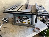 Side view of the Trademaster 10" bench saw showing the blade and metal wings with adjusting handle.