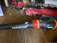 Photo showing the Worx corded leaf blower on a wooden surface with visible branding and model name.
