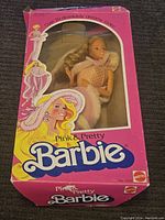 Full box view showcasing Barbie doll in the original pink Mattel box with logo and stylized animation.