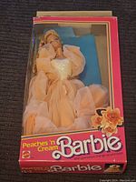 Full view of Barbie doll in original pink box with window displaying doll in peach gown.