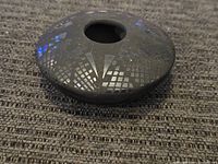 Top and side view of a black pottery vase with etched geometric patterns and a small opening.