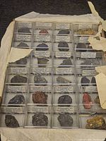 Photo showing multiple labeled mineral samples in clear plastic display cases: Sulphides of Copper & Related Metals and Realgar from Nevada.