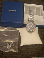 Seiko men's watch with stainless steel band, original box with manual, and extra links sealed in plastic bag