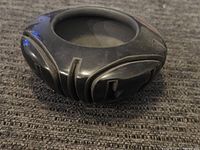 Side view of the black pottery bowl showing carved geometric designs and polished finish.