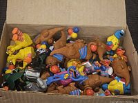 Top-down view of an open box containing various Sesame Street figures including Big Bird, Grover, brown birds, and others.