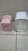 Pink Frigidaire mini fridge and white mini makeup chiller side by side on tile floor.