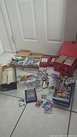 Wide shot showing hundreds of assorted sports cards loose on the floor, in boxes, and a red carrying case