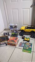 Photo showing large yellow New Bright Bronco truck with remote, 4 Funko Pop boxes stacked, and other toys on floor