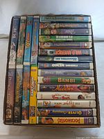Overview of 23 assorted family friendly VHS tapes in a box showing diverse titles such as The Prince of Egypt, Toy Story, Pooh's Grand Adventure, Aladdin, Bambi, and others.