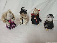 Front view showing four dancing hamster figurines in different costumes standing in a row.