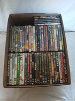 Box with 53 assorted DVD cases showing a variety of titles and genres.