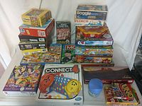 Photo showing a variety of puzzles and games including Connect 4, Disney puzzle, UNO, Skip-Bo and multiple boxed board games stacked.: