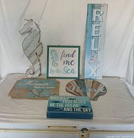 Full view of six nautical themed wooden wall décor pieces on plain backdrop.