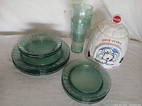 Green tinted glass plates, bowls, plastic Coca Cola glasses, and the ceramic igloo cooler grouped together