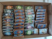 Box containing stacks of sealed Clash of Decks card packs, showing the backs of various packs.