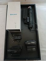 Top view of all four items laid out in a tray: Olight flashlight, SIG SAUER ROMEO1 red dot sight, DL-X3 laser sight, and additional black laser sight with mounting hardware.