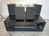 Front view of Onkyo AV receiver HT-R398 with digital display and four speakers on top.