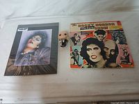 All three items shown together: framed print, music album, Funko figure on white surface.