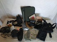 Full view of the lot showing all items including bags, holsters, gloves, cleaning bottles, and other accessories on a white backdrop.