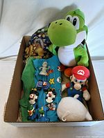 Photo showing all items in the lot inside a cardboard box including plush figures, T-shirts, toy cars, and backpack.