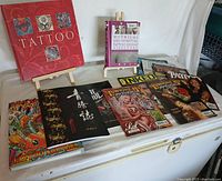 Full view of collection including tattoo magazines and books displayed on surface, highlighting variety and condition.