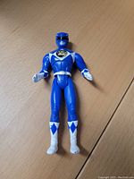 Single Blue Power Ranger action figure lying flat on wooden surface, showing full body and front detail.