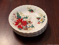 Four stacked Royal Albert Poinsettia dessert bowls showing the floral pattern and gold trim.