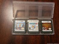Plastic case containing three Nintendo DS game cartridges: Lock's Quest, Picross 3D, and Deal or No Deal. Each cartridge has the original label visible.