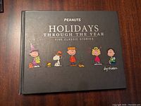Front cover of Peanuts Holidays Through the Year hardcover book showing title and Peanuts characters in holiday costumes.