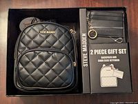 Open box showing black quilted Steve Madden backpack and matching card case keychain with packaging insert