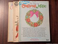 Three Christmas music books stacked with visible titles and holiday wreath artwork on covers.