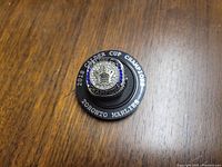 Top-down view of the Calder Cup Men's replica ring on a wooden surface showing the detailed center emblem and blue stone accents.
