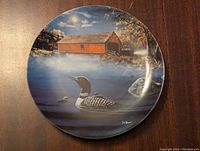 Decorative plate showing artist Jim Hansel's 'Tranquil Refuge' with loon and covered bridge scene