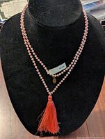 Long red and clear beaded necklace with tassel on black bust stand