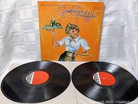 Front view of American Graffiti soundtrack vinyl records with orange cover showing waitress holding tray, two records laid out.