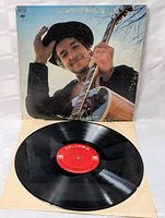 Front view of the album cover photo featuring Bob Dylan holding an acoustic guitar, tipping his hat.