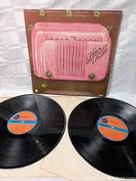 Front of the album cover with visible wear and the two black vinyl records laid flat showing orange and blue labels.