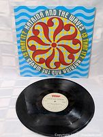 Front of colorful vintage LP sleeve with circular pattern and wave design, featuring band and album title.