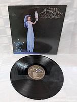 Front view of vinyl record and original cover sleeve showing Stevie Nicks holding a white bird with decorative text on black background.