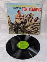Front cover of the album showing Stompin Tom Connors with guitar amidst branches and blue sky.