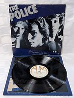 Front cover of 'Regatta de Blanc' LP showing black and white portrait of band members with blue and black background, featuring The Police logo and album title.