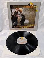 Front view of vinyl record partially out of cover showing label and record condition