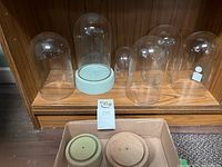 Six clear glass globes placed on wooden shelf, various sizes, tallest approx 8 inches.
